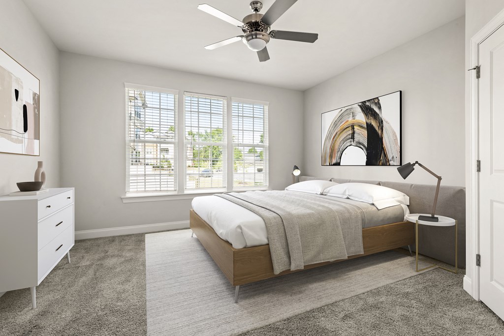 A bedroom with a large bed, a ceiling fan, and a window with blinds.