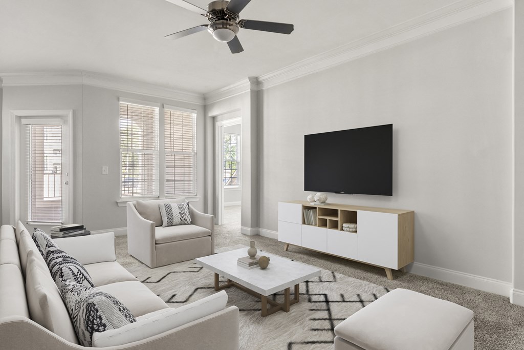A living room with a white sofa, a white coffee table, and a black television.