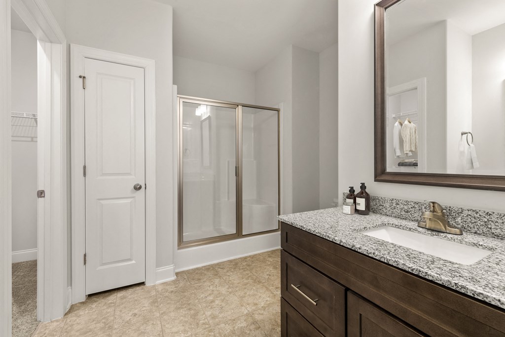 A bathroom with a sink, mirror, and shower.