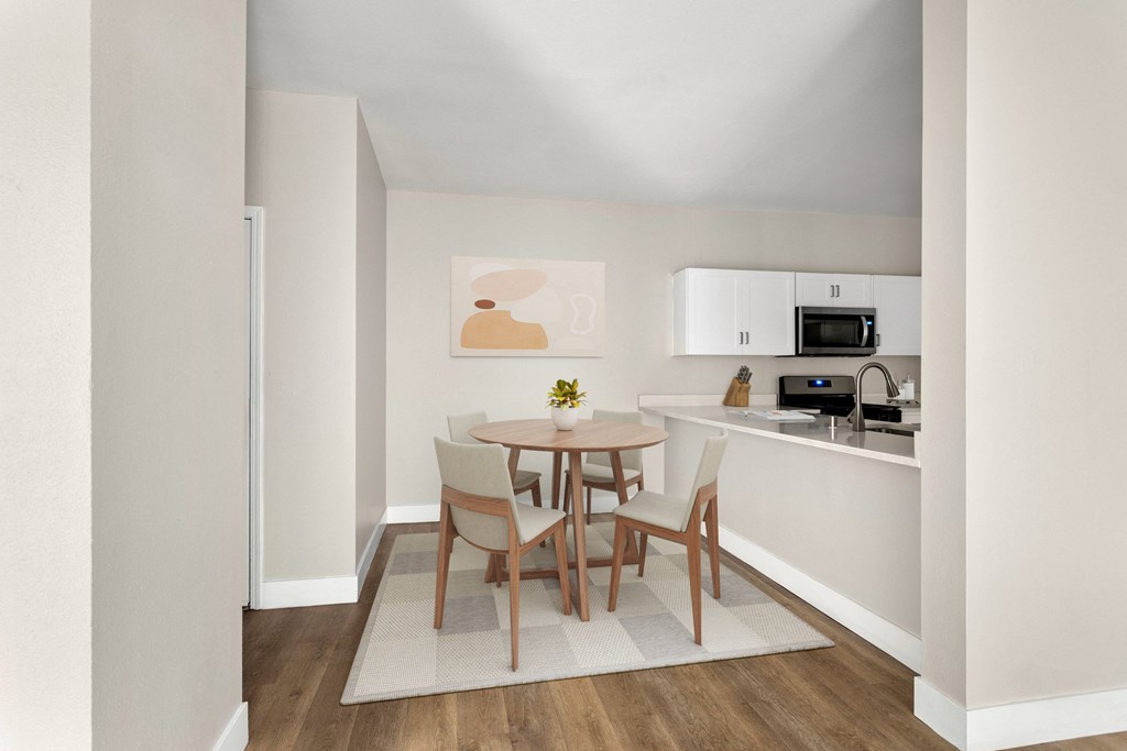 a dining room with a table and chairs and a kitchen with a sink and microwave