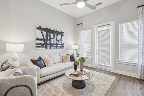A living room with a grey couch, a coffee table, and a painting on the wall.