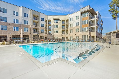 A large swimming pool in front of apartment buildings.