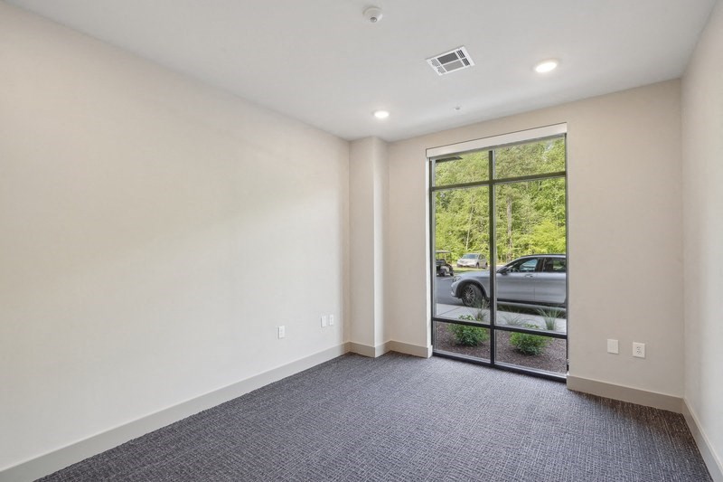 the living room has a large window and gray carpet and white walls