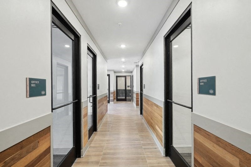 a hallway with black doors and white walls and wood floors