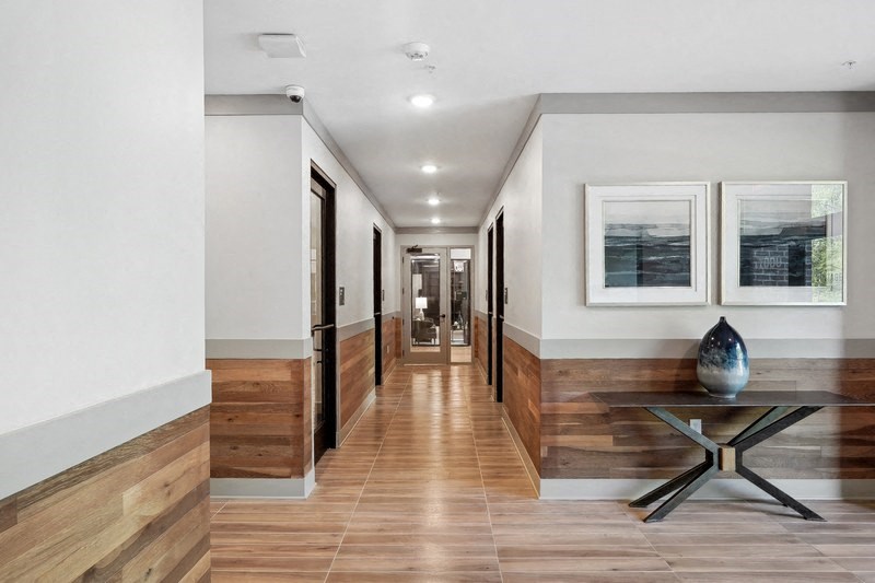 a long hallway with white walls and wooden floors and a table