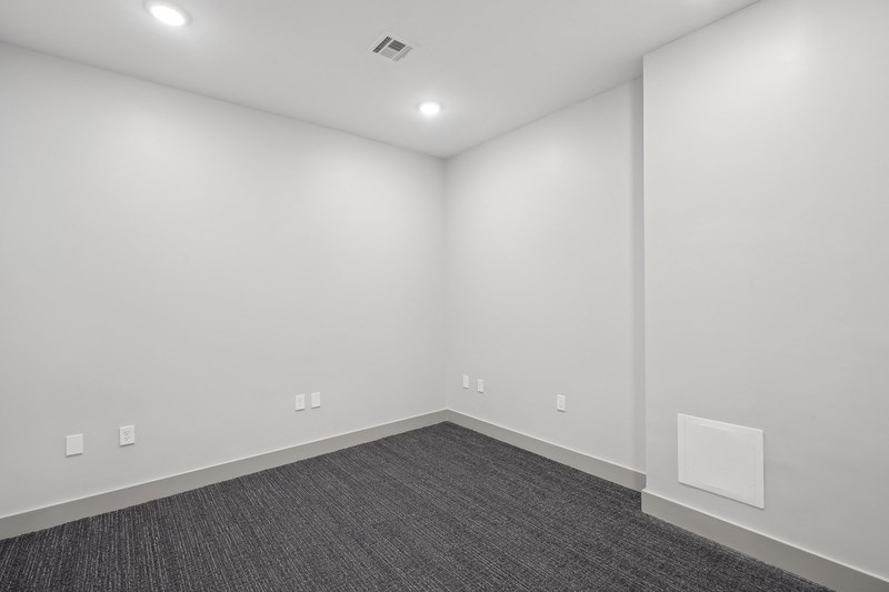 an empty room with white walls and a gray carpet
