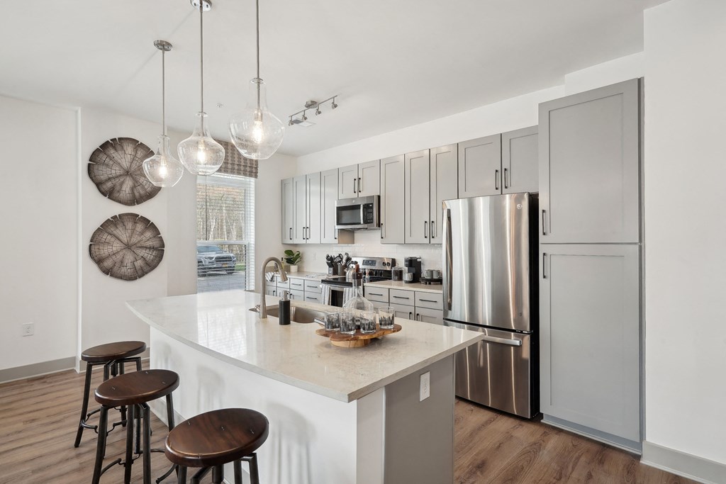 an open kitchen with a large island and stainless steel refrigerator