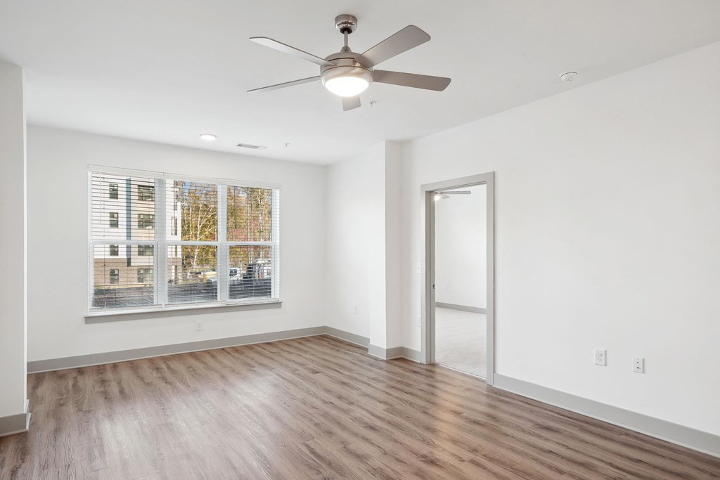 an empty living room with a ceiling fan and a window