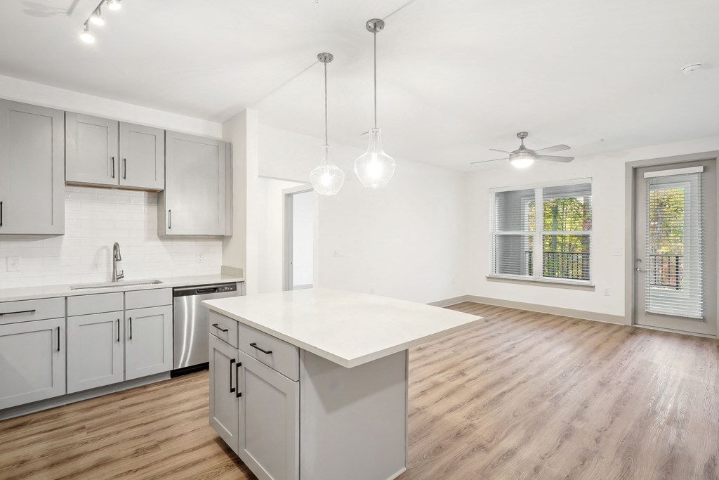 an open kitchen and living room with white cabinets and a white counter top