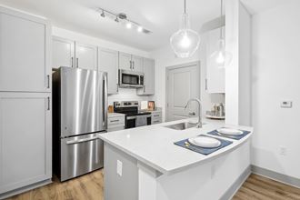 a white kitchen with stainless steel appliances and a white counter top