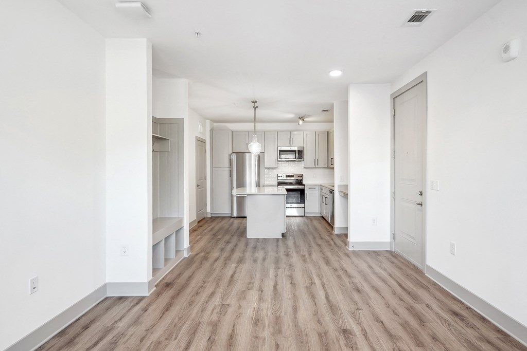 an empty living room and kitchen with white walls and wood floors