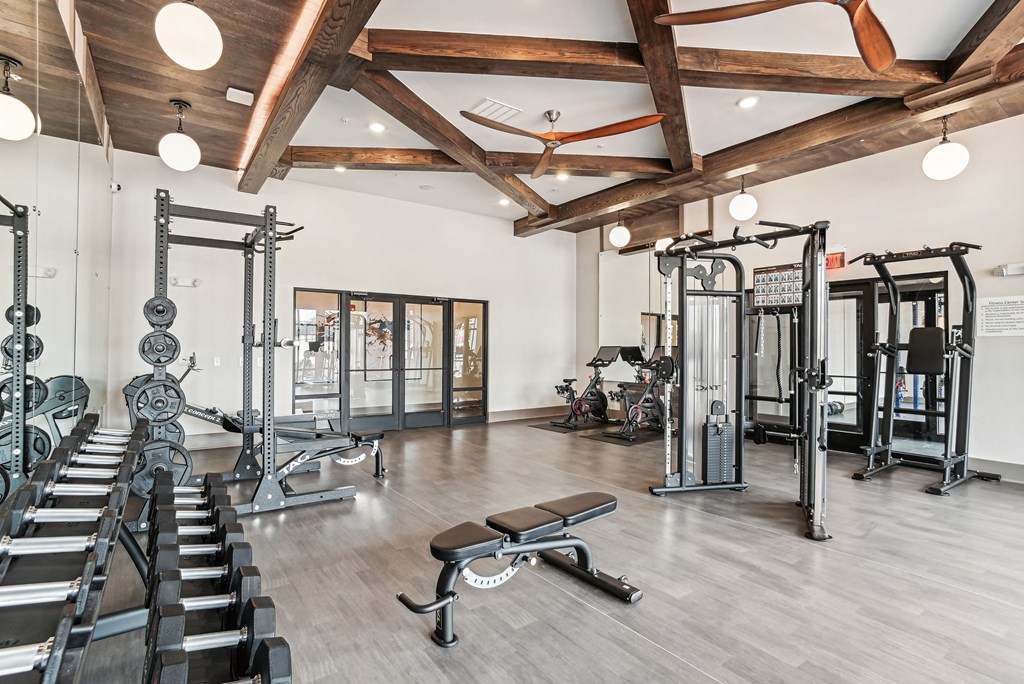 a gym with weights and cardio machines and a ceiling fan