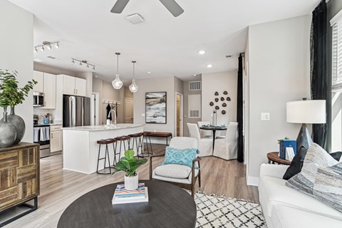 a living room with a couch and a coffee table and a kitchen with a bar