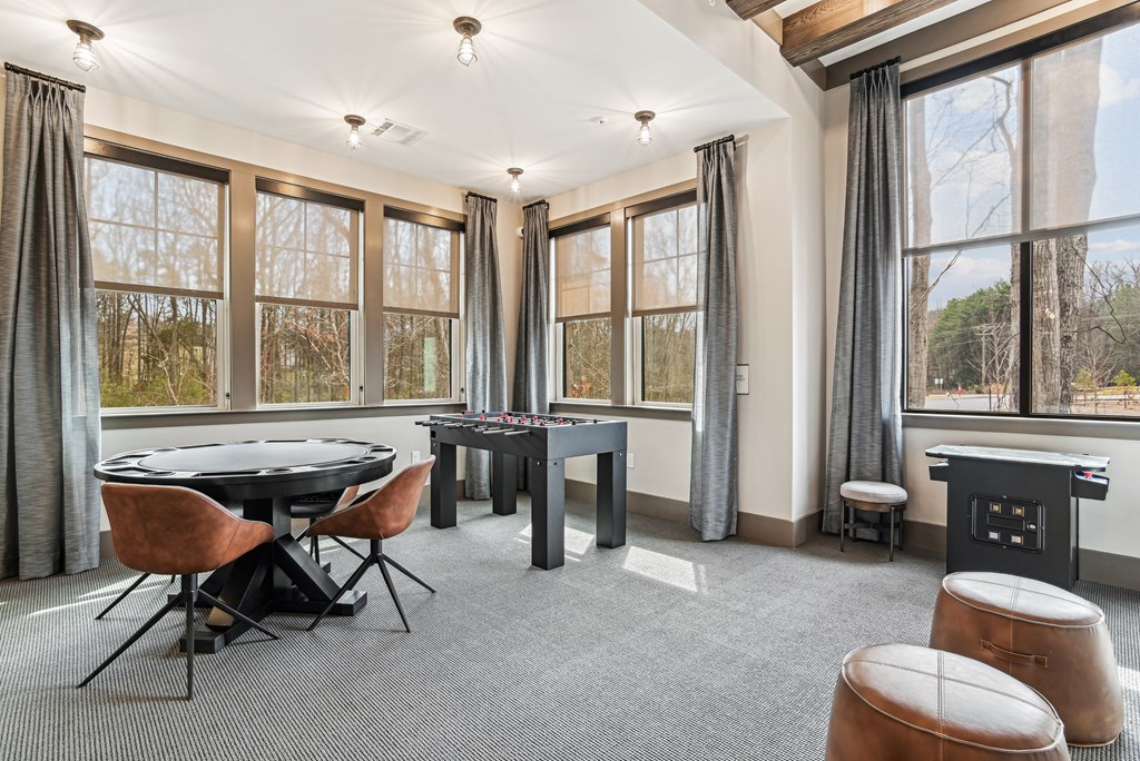 a game room with a foosball table and chairs and windows