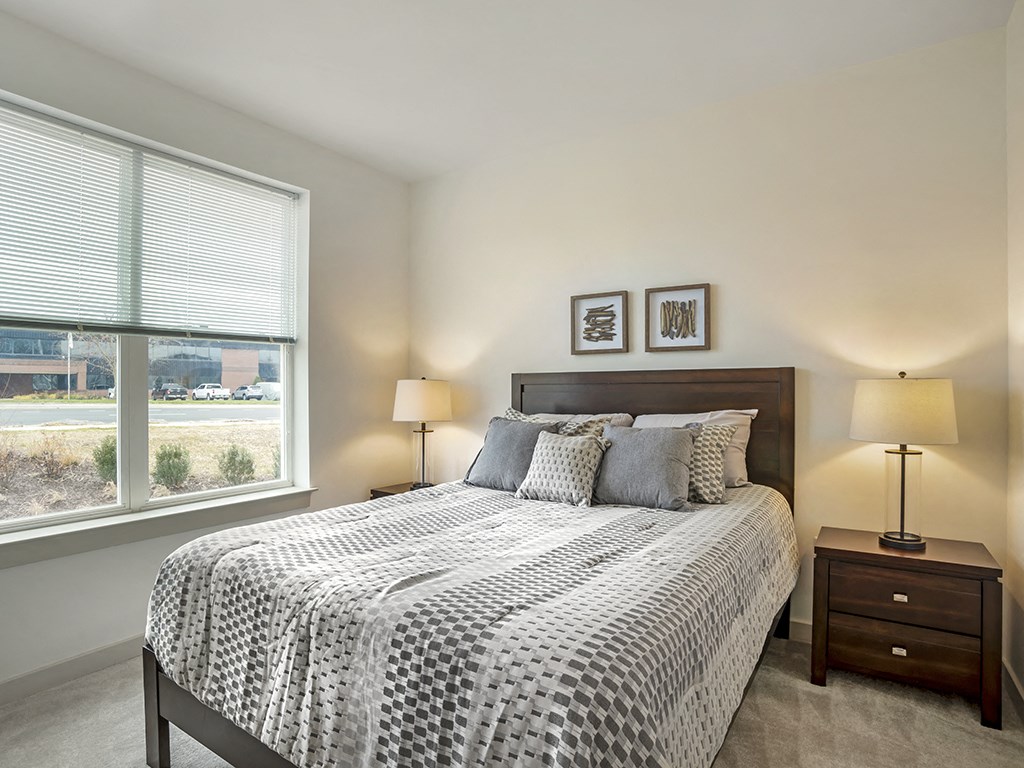 A bedroom with a large bed and two lamps.