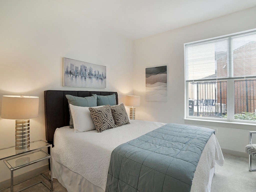 A bedroom with a large bed and a window overlooking a balcony.