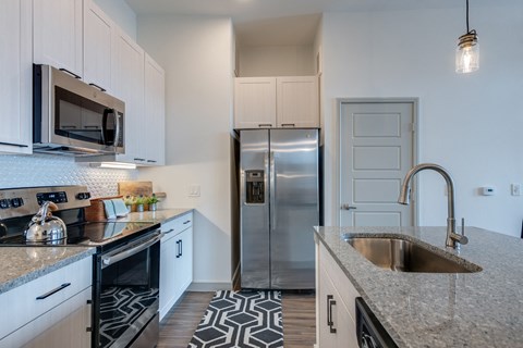 A kitchen with a black and white patterned tile floor.