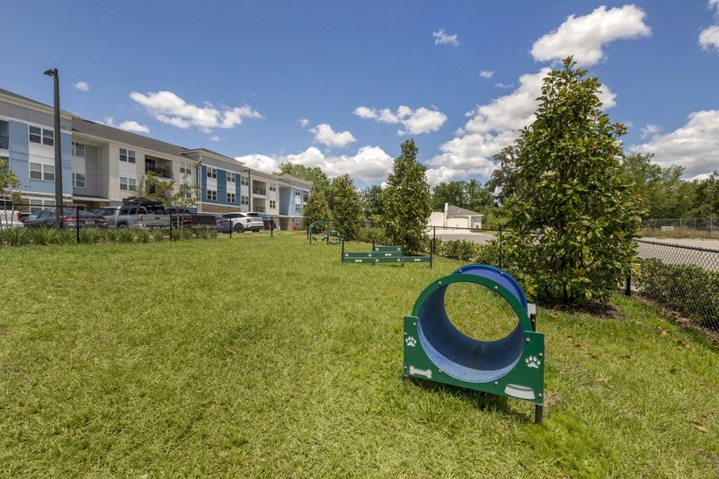 a seesaw sits in the middle of a grassy area in front of an apartment building