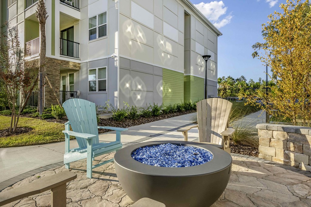 patio with chairs and fire pit with building in the background