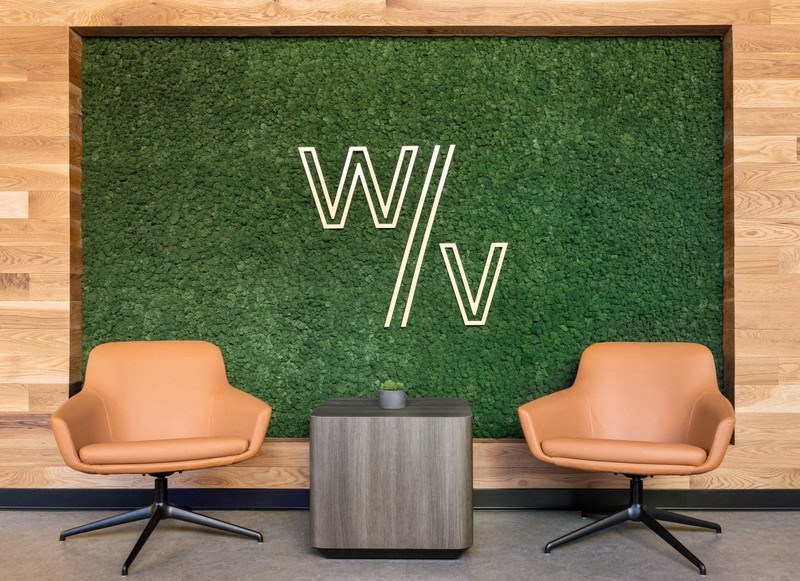 two chairs and a table in front of a grassy wall