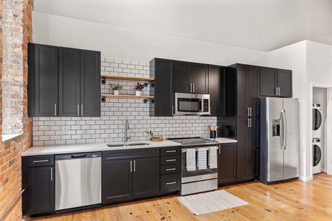 a white and black kitchen with black cabinets and stainless steel appliances