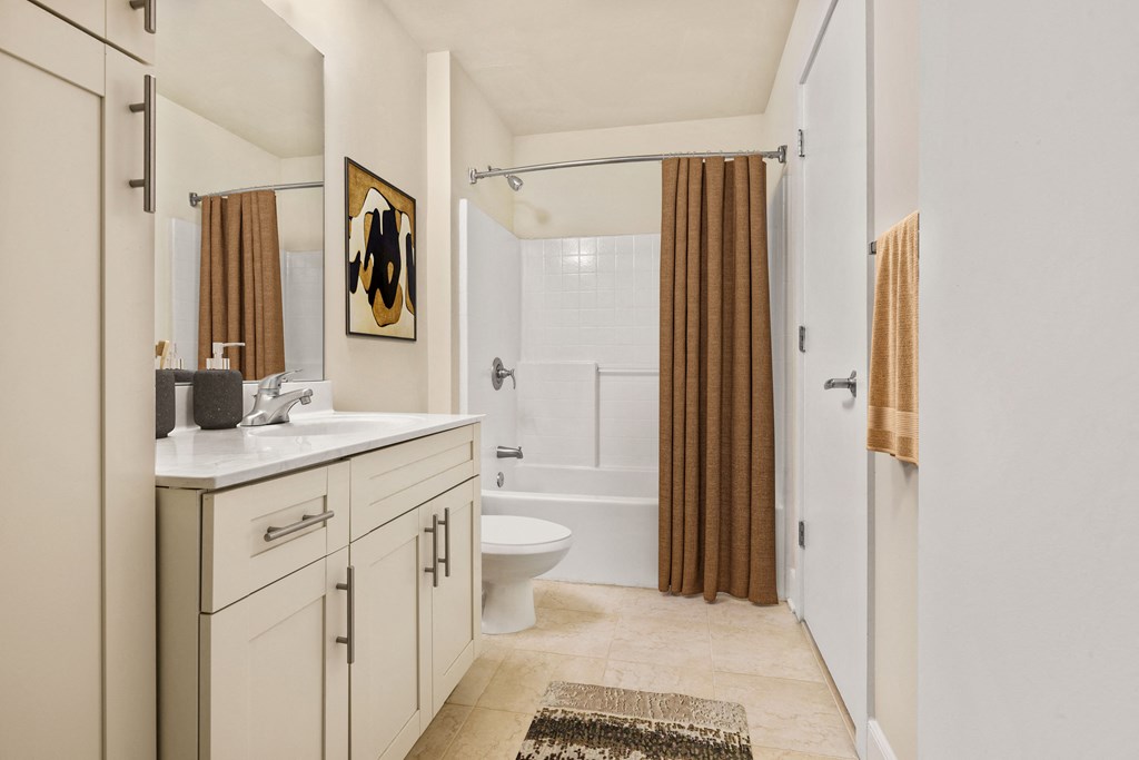 a bathroom with white cabinets and a brown shower curtain