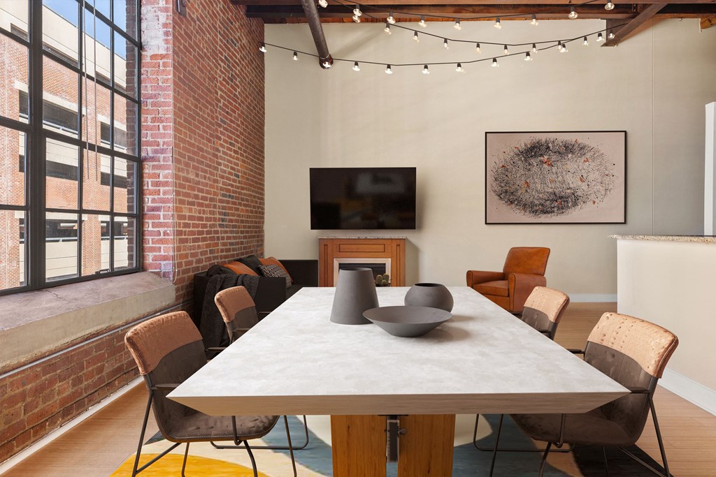 a room with a large white table and chairs and a television on the wall