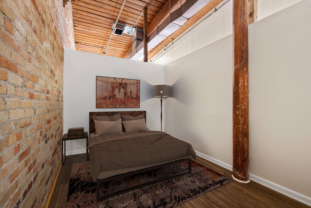 a bedroom with a bed in a room with a exposed brick wall