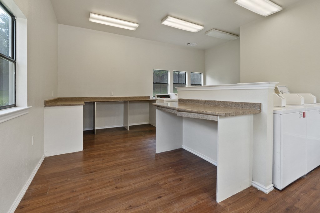 an empty kitchen with white cabinets and a wood floor