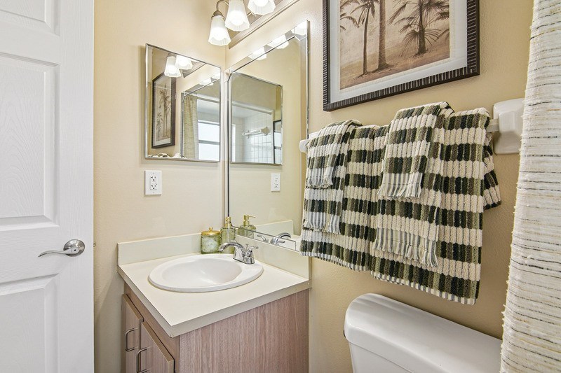 A bathroom with a sink, mirror, and a towel hanging on the wall.