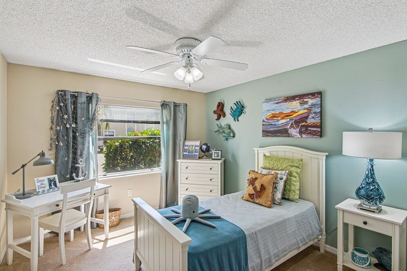 A bedroom with a bed, desk, chair, and window.