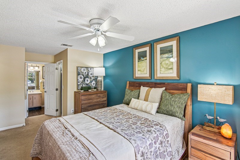 A bedroom with a bed, dresser, and ceiling fan.