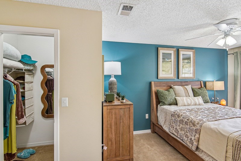 A bedroom with a bed, dresser, and a ceiling fan.