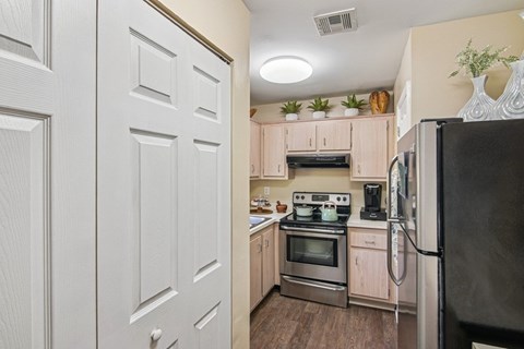 A kitchen with a black refrigerator, white cabinets, and a black stove top oven.
