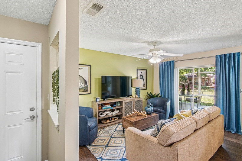 A living room with a couch, a television, and a fan.