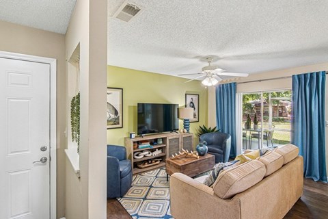 A living room with a couch, a television, and a fan.