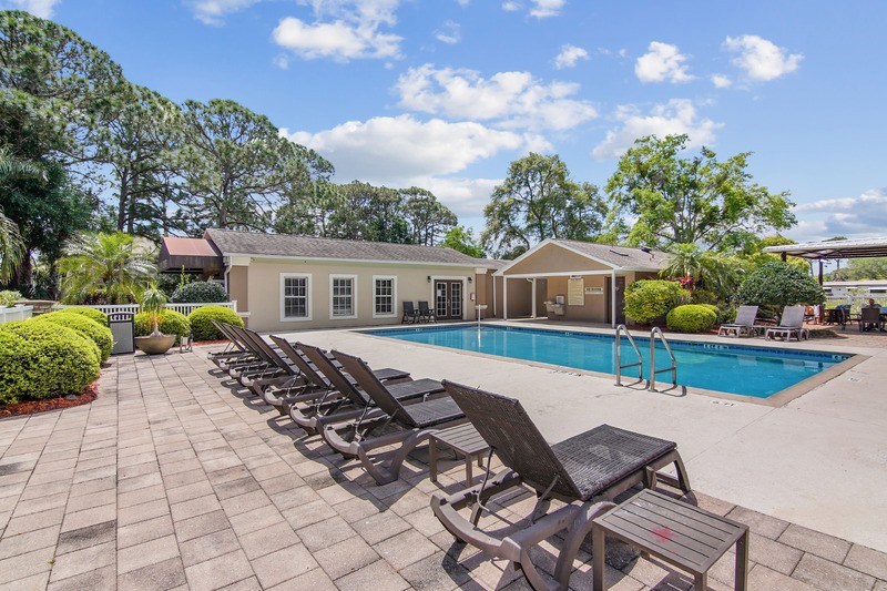 A poolside area with lounge chairs and a building in the background.