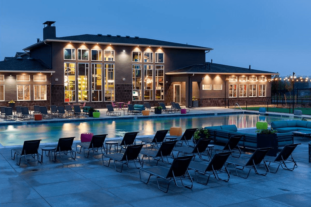 A large house with a pool and patio furniture.