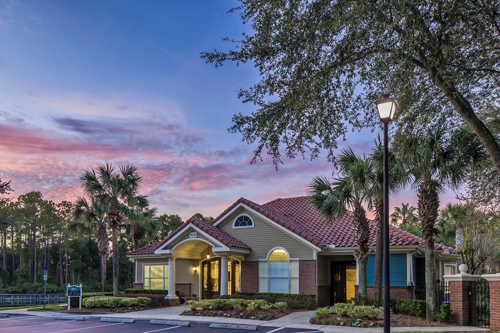 a house with palm trees and a sunset in the background