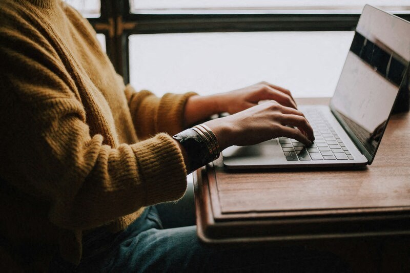 a person sitting at a table using a laptop computer