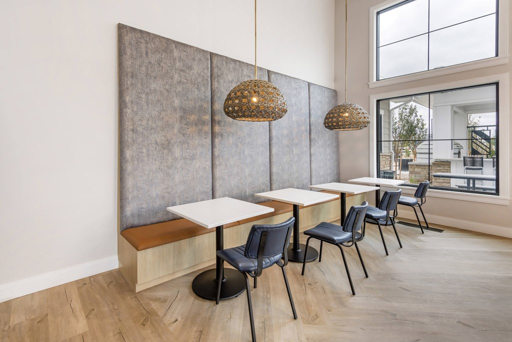 a dining area with tables and chairs and two large windows