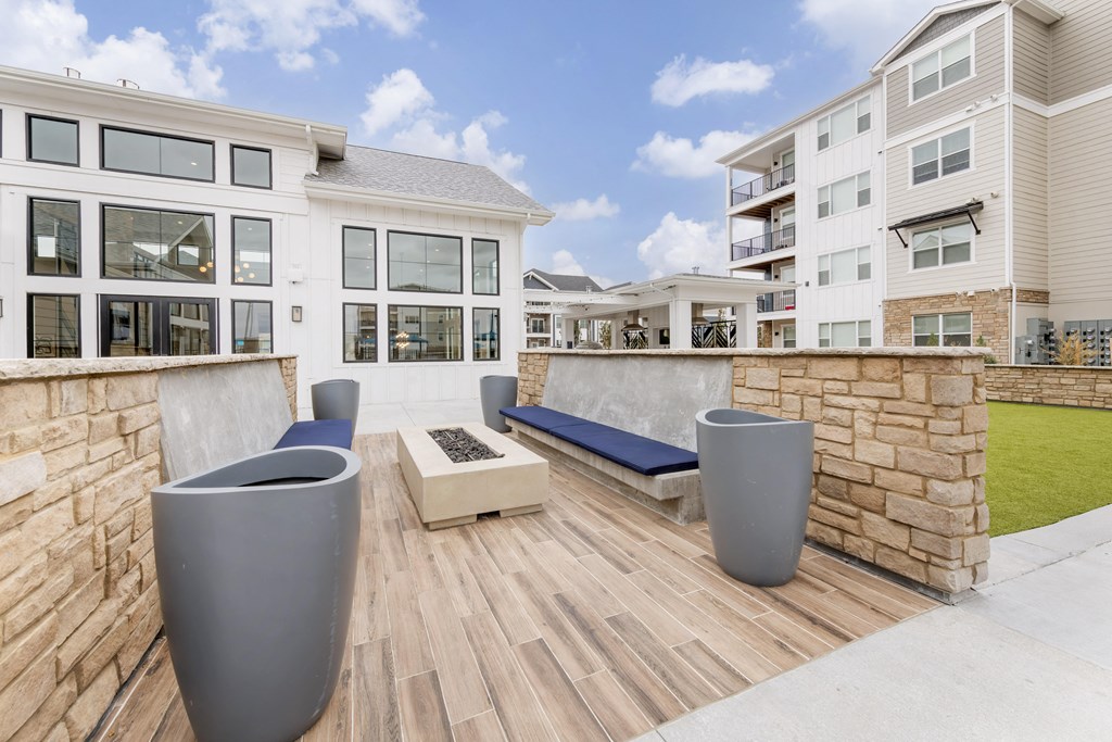 an outdoor patio with benches and a stone wall and an apartment building