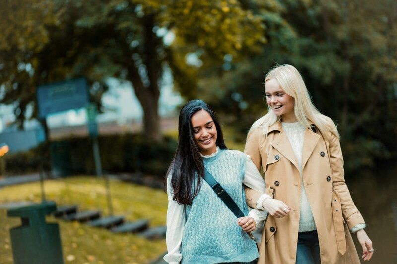 two women walking together in a park