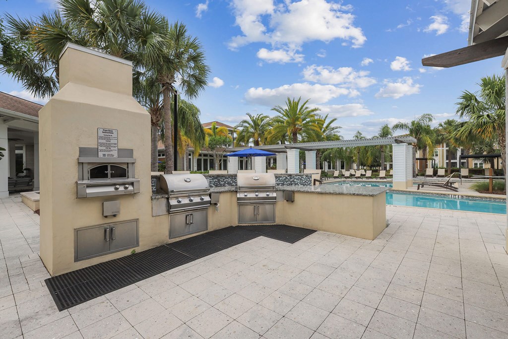 a barbecue grill is next to a swimming pool with palm trees