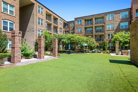 A grassy courtyard is surrounded by apartment buildings.