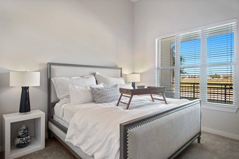 A bedroom with a large bed and a window with blinds.