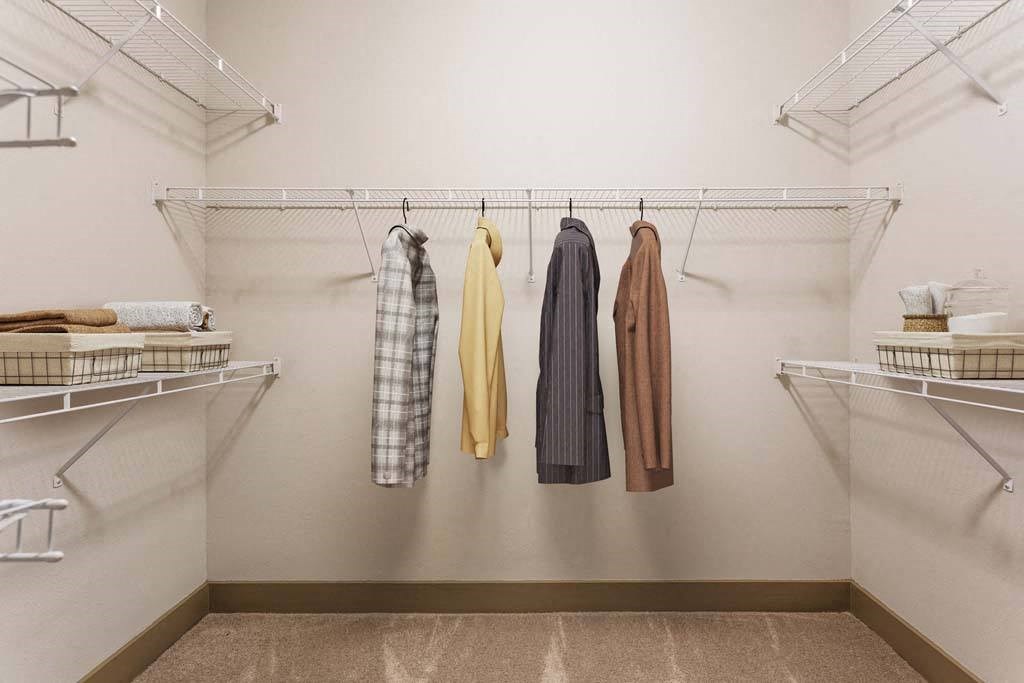 a walk in closet with clothes hanging on a rack