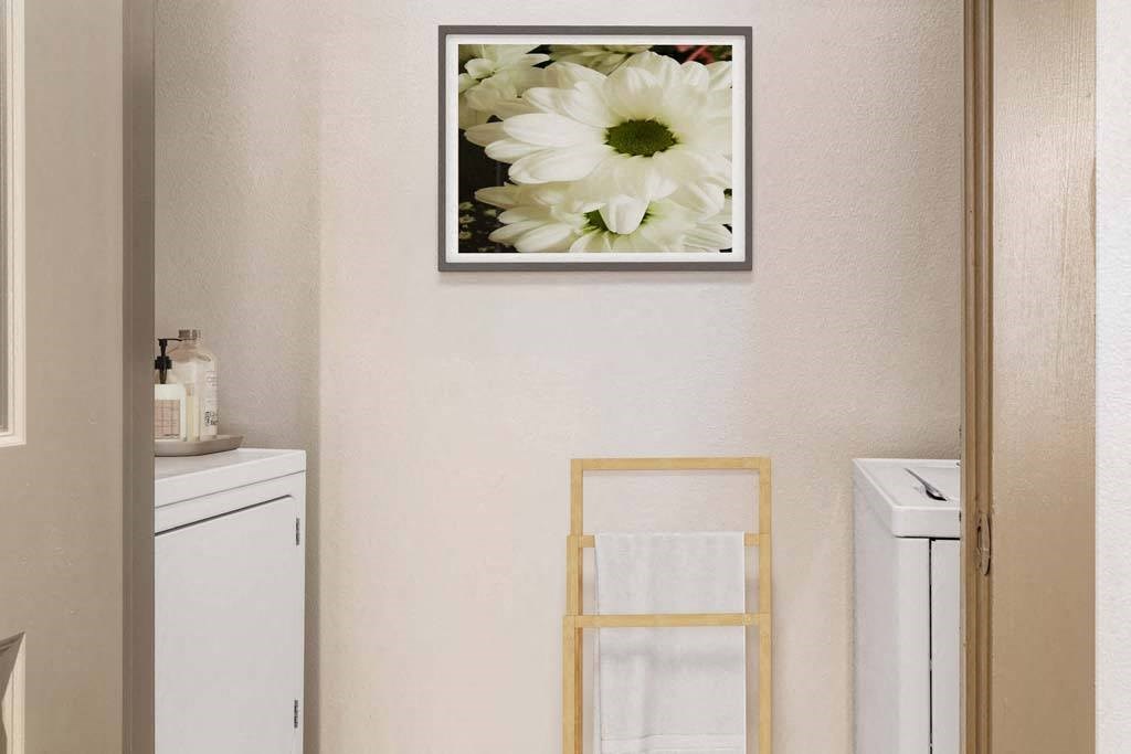 a white bathroom with a picture of a white flower on the wall