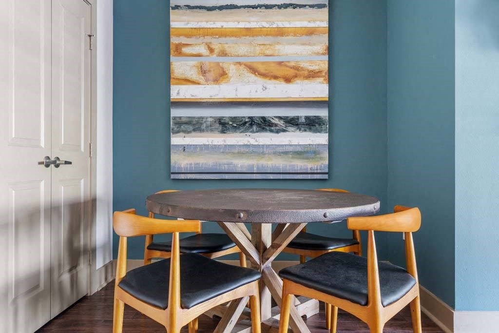 a table and chairs in a room with a painting on the wall