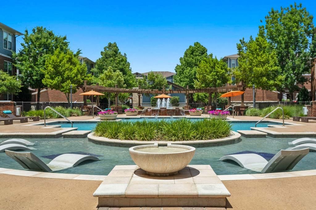 a pool with chairs and a fountain in front of a building